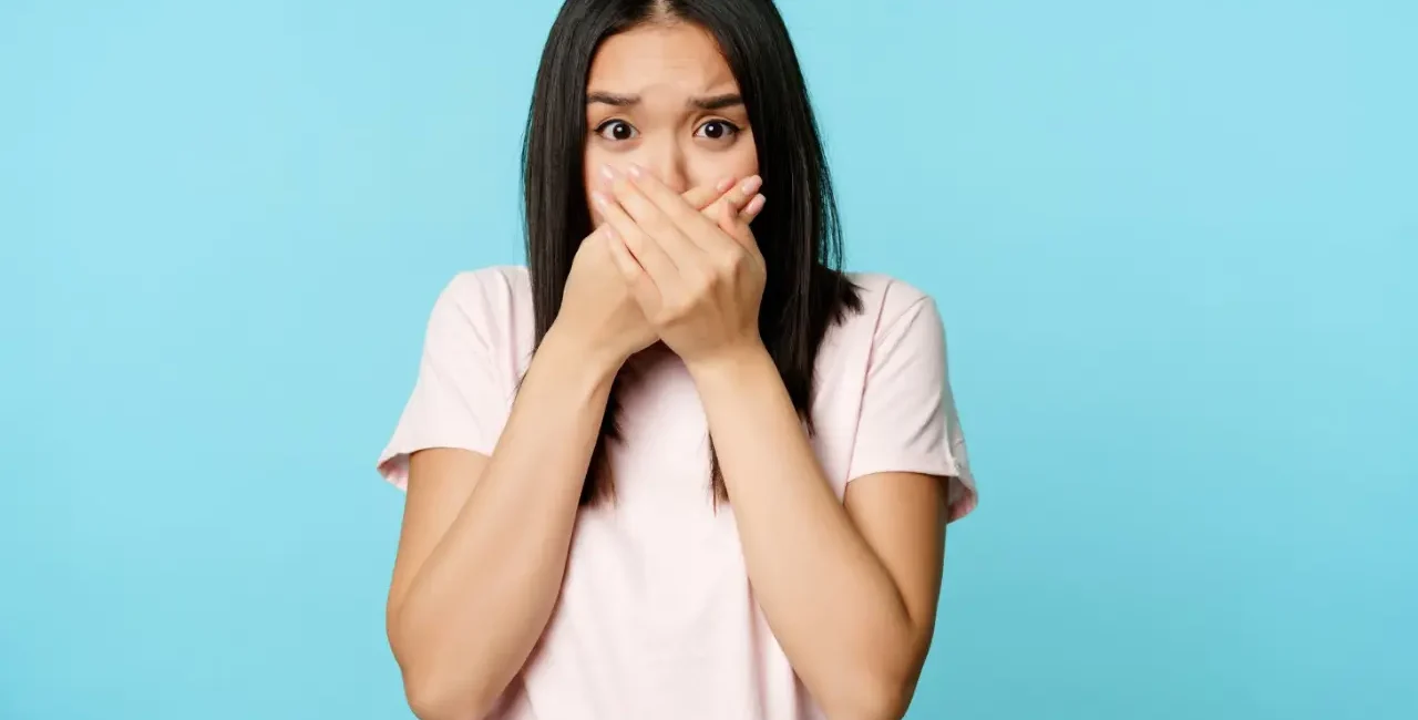 woman covering her mouth and looking shock