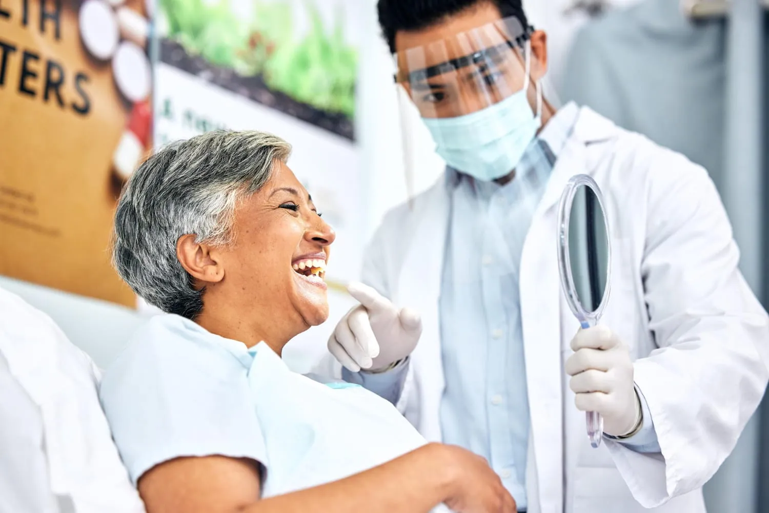 a dentist holding a mirror to show patient her teeth